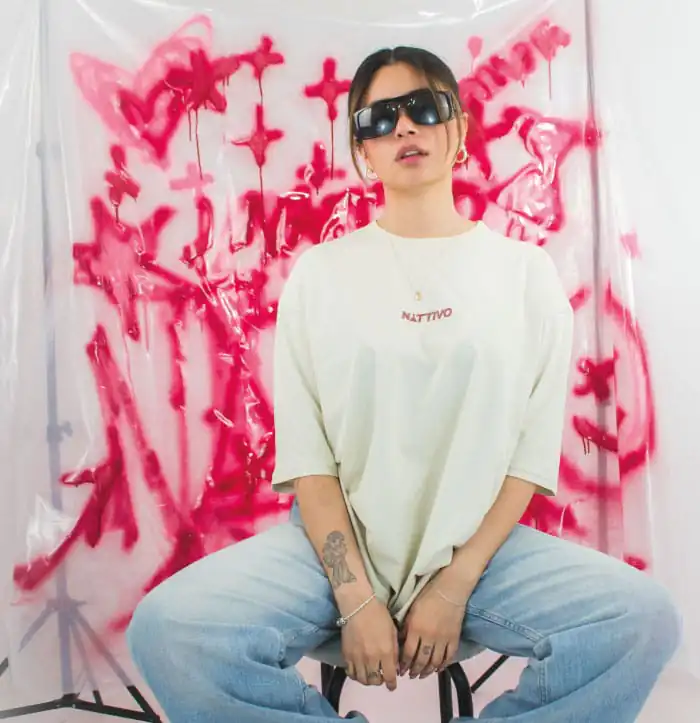 Mujer con gafas de sol y ropa casual en fondo de graffiti rosa, representando estilo urbano y moda m.