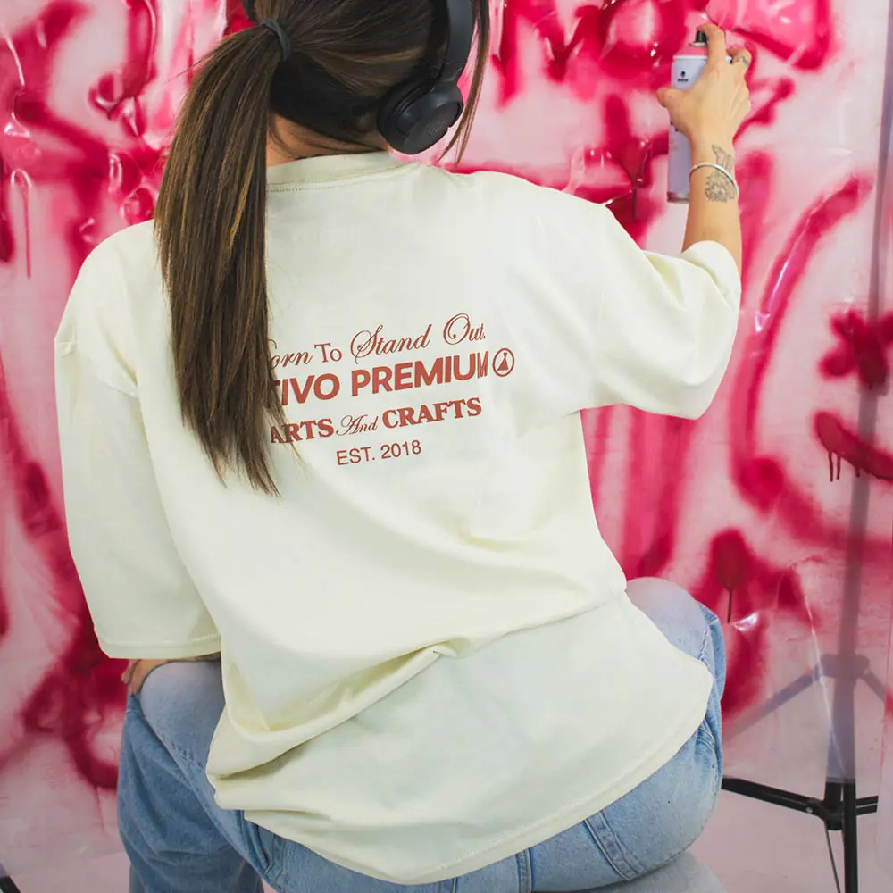 Mujer con camiseta oversize arena en ambiente artístico y moderno.